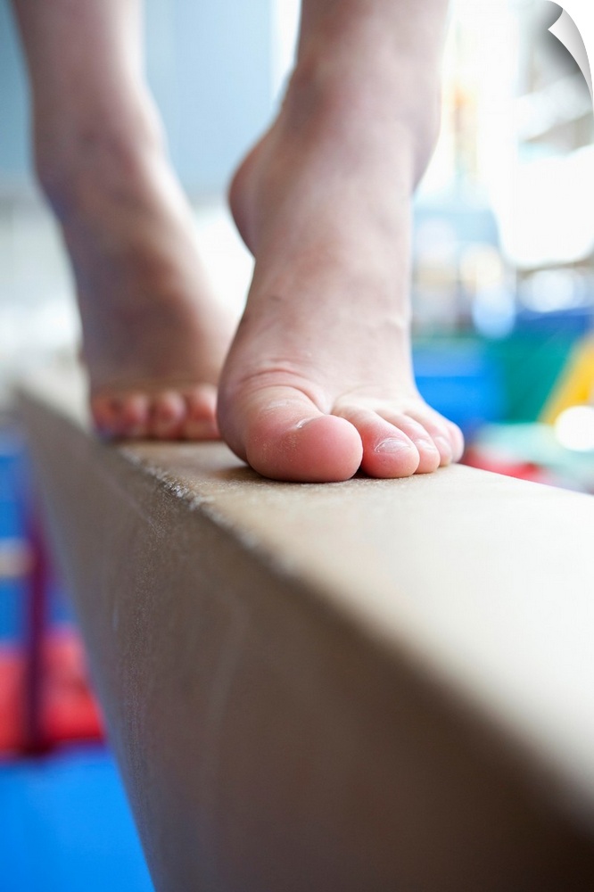 6-7 year old girl slowly walks across balance beam on her toes, close up of feet