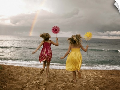 Girls running on beach holding windmills