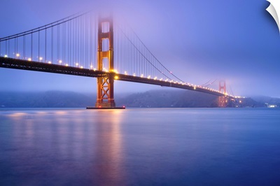 Golden gate bridge in San Francisco at dusk, bridge lights light up low fog.