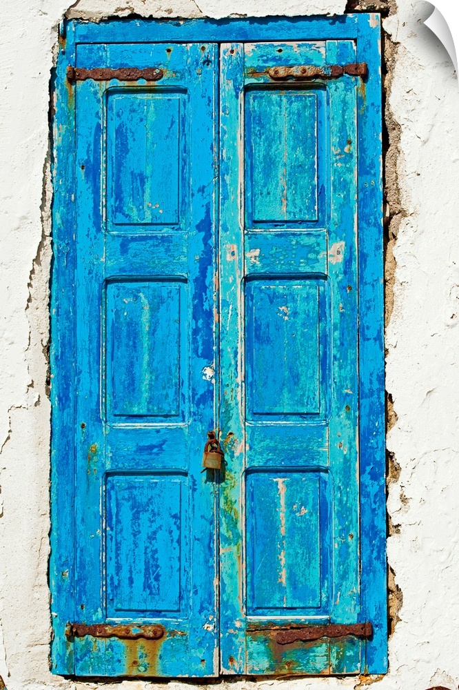 Rustic, paint peeling blue door in the middle of the white side of a home.