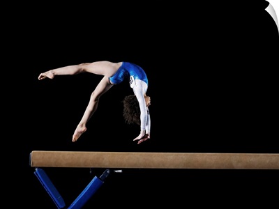 Gymnast flipping on balance beam, side view