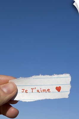 Hand holding I love you note written in French