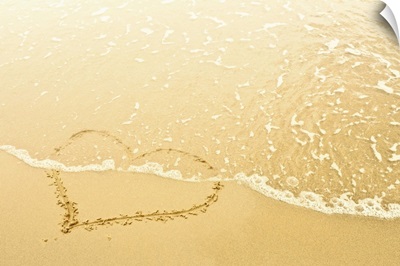 Heart in sand washed away by waves