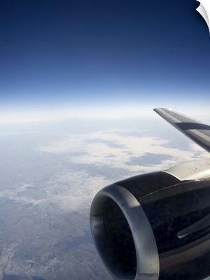 High altitude view of a jet engine set against a gentle cloudscape