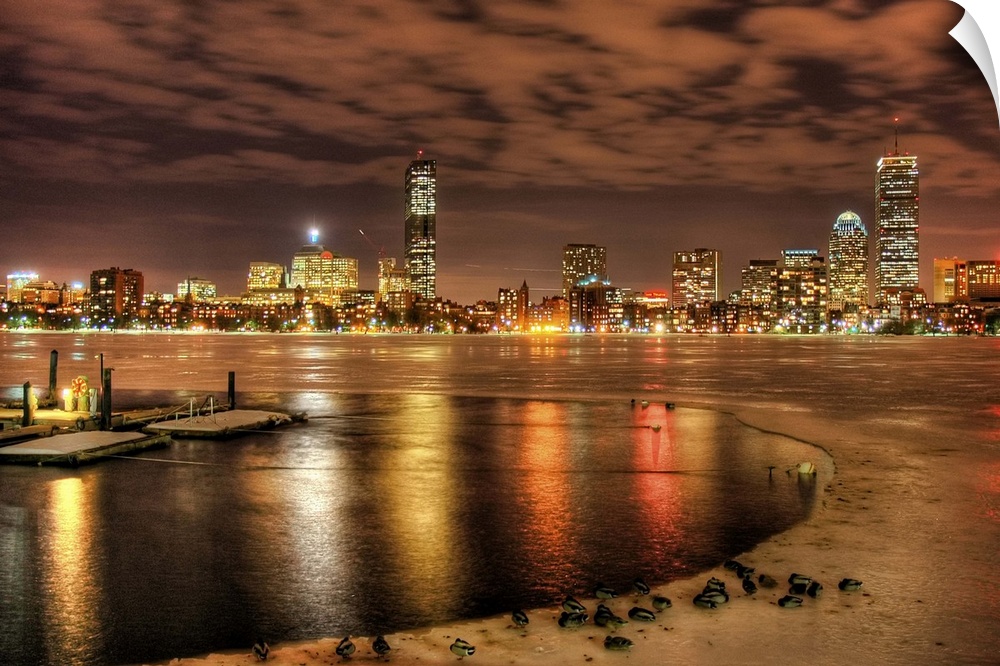 Ice partially melted on Charles River in Boston.  Ducks in foreground, boat dock and Boston skyline.