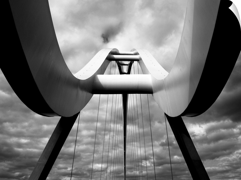 A black and white photograph taken from below the infinity bridge in the UK and looking up to the top of it.