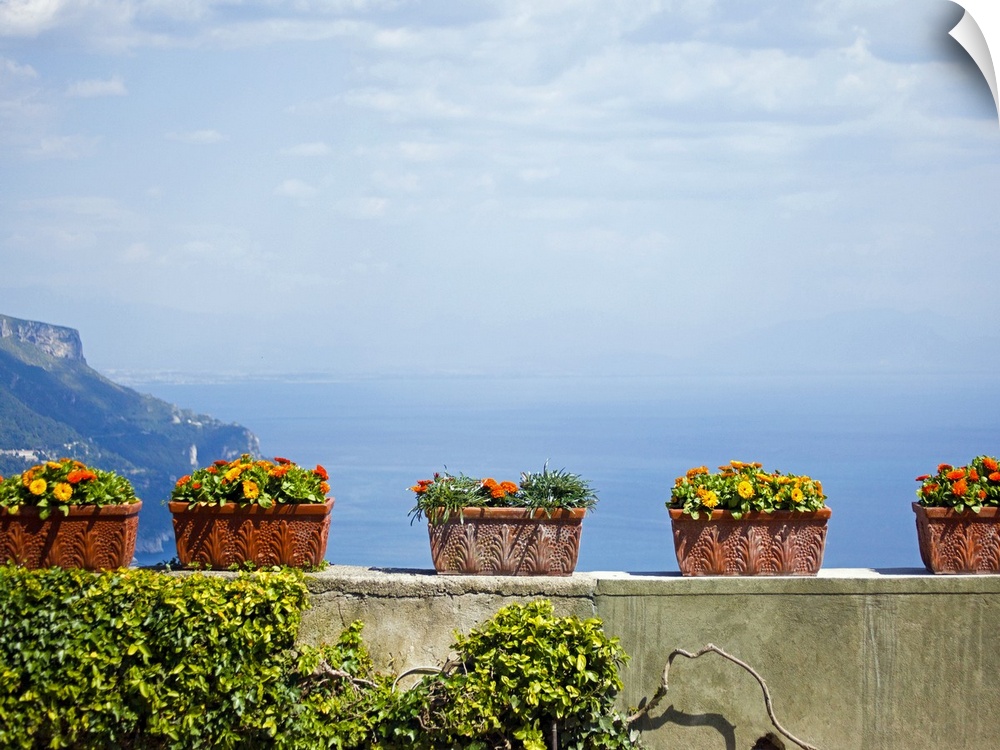 Landscape, large photograph of numerous, rectangle flower pots with flowers, sitting on stone wall overlooking a hazy sky ...