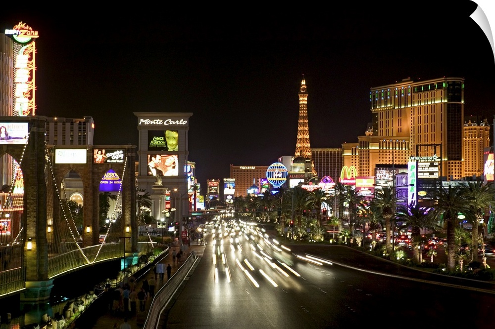 Photograph of "Sin City" after sunset with buildings lit up in the dark sky.  A highway lined with buildings is filled wit...