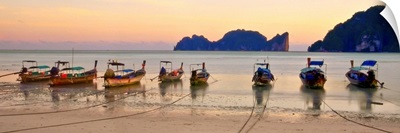 Long tail boats on beach at sunset.