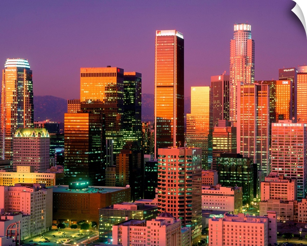 Landscape, close up photograph on a large wall hanging of brightly lit skyscrapers in downtown Los Angeles, against a vibr...