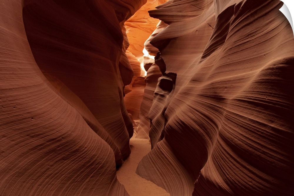 A view through a tight corridor between the striated stone walls of a desert canyon in Arizona.