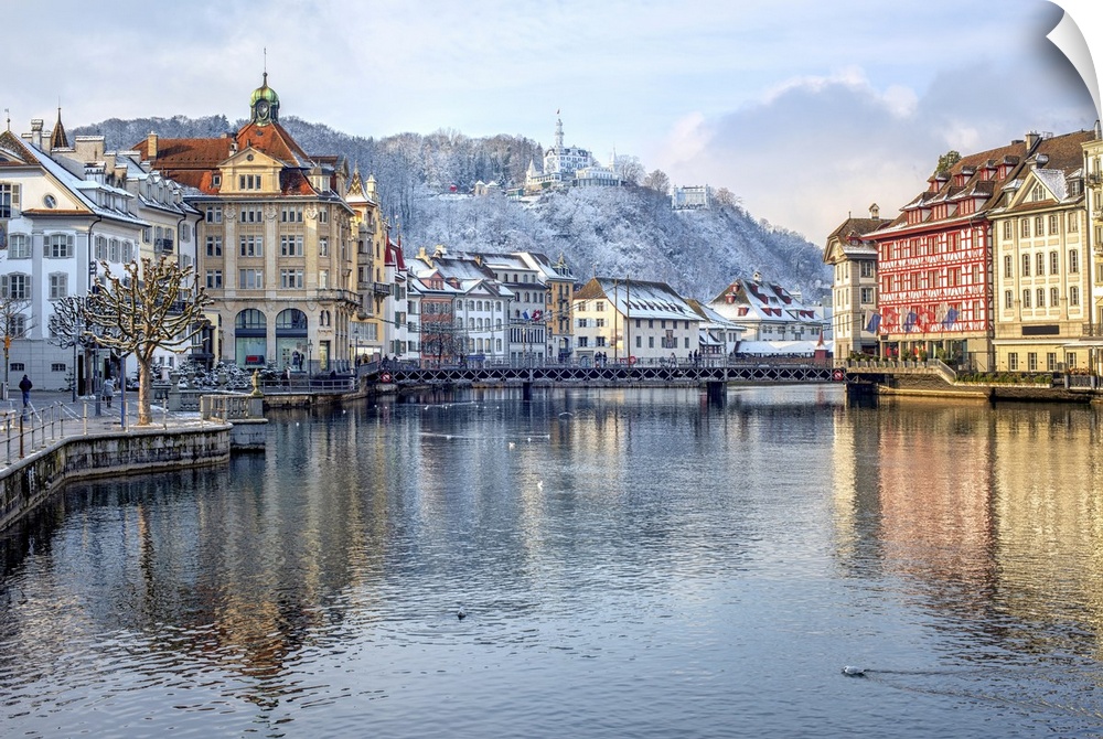 Lucerne city, Switzerland, view of the Old Town covered with white snow in winter, reflecting in the river.