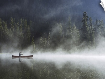 Man canoeing on lake cover with fog, side view