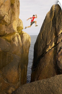 Man leaping over rocky crevice