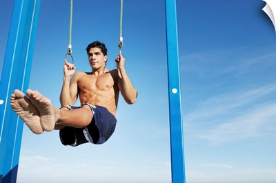 Man on a beach working out on exercise rings apparatus