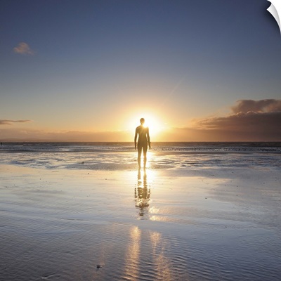 Man walking on beach at sunset, UK.