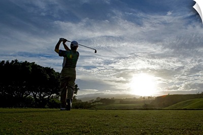 Mature man swinging golf club at dusk