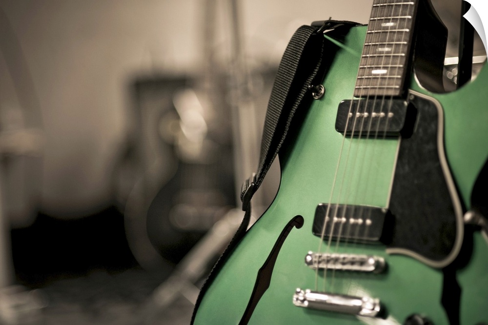 Metallic green hollow-body electric guitar used by band Neon love life. Guitar is on stand with strap. Was shot with shall...