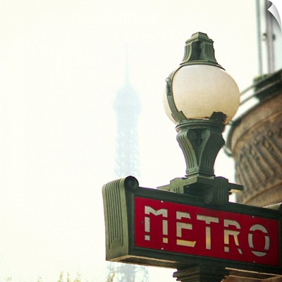 Metro sign in Paris with Eiffel Tower in the  background.