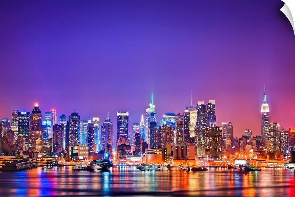 Photograph of New York skyline at night with the Hudson River in foreground.  The building lights are reflected in the water.
