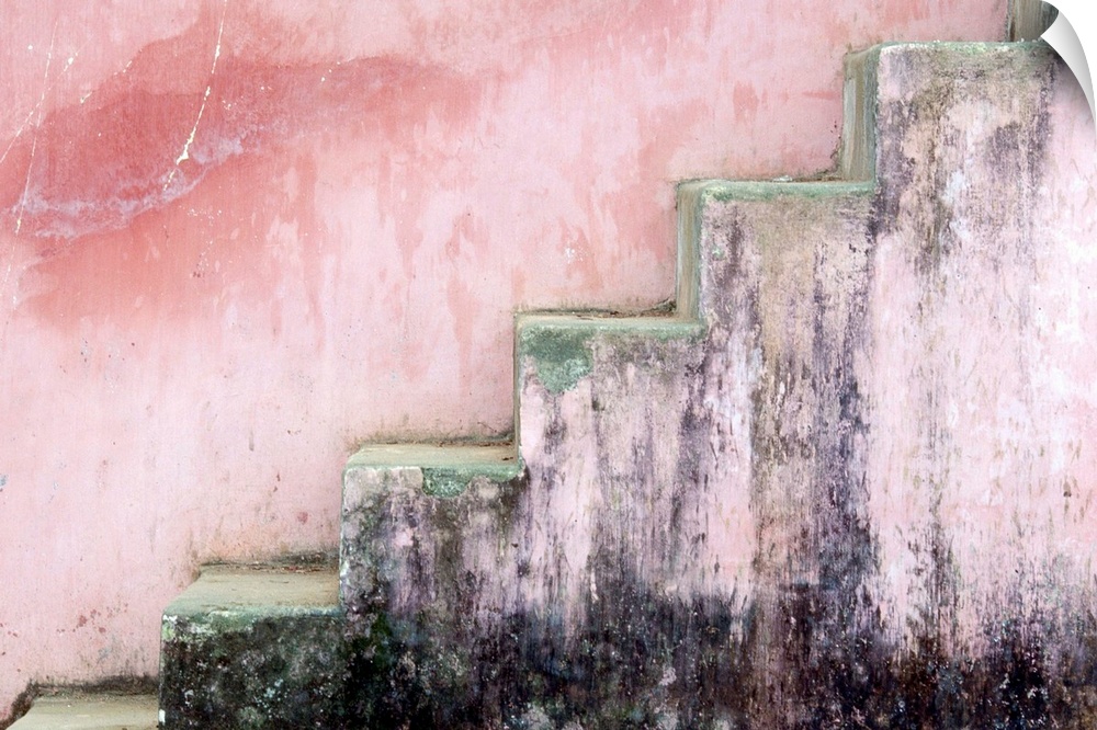Mildewed stairs along a pink pastel colored wall at Thien Nu Pagoda in Hue in the late afternoon.