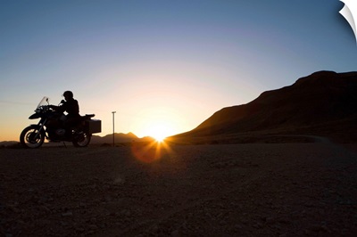 Motorcyclist riding at sunset