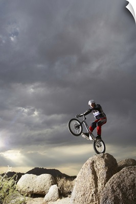 Mountain bike rider doing wheely on rock