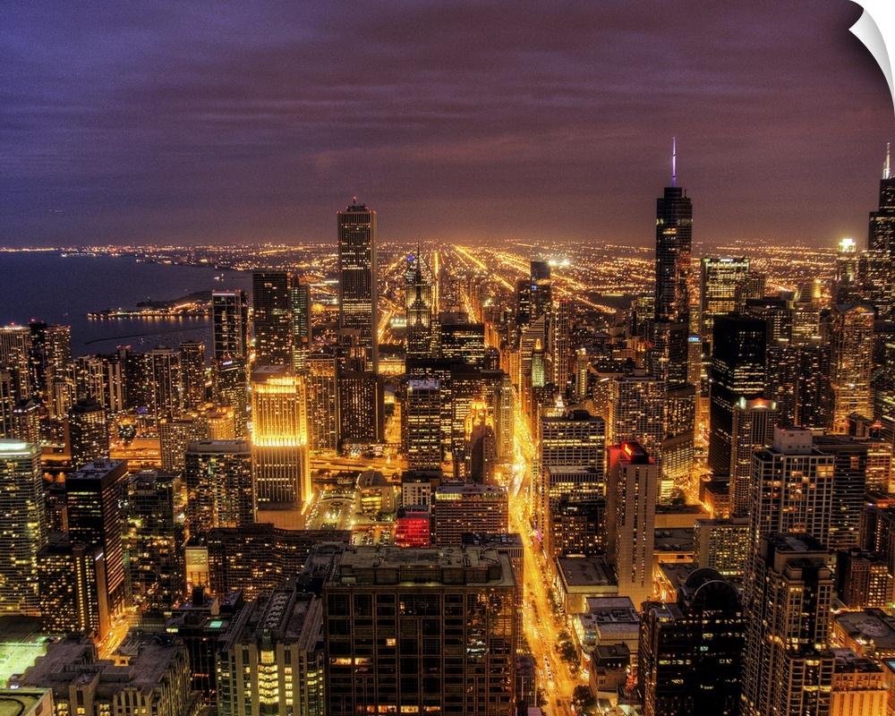 High-angle photograph of city with buildings and streets lit up at dusk.