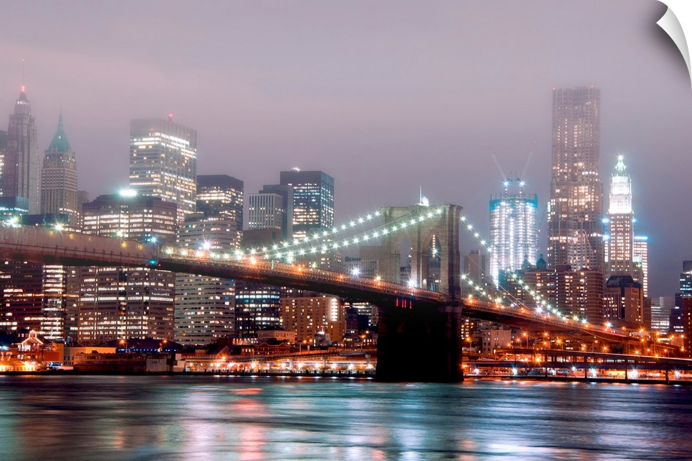 A misty night scene illuminated by urban lights of downtown Manhattan photographed from the Brooklyn shore.
