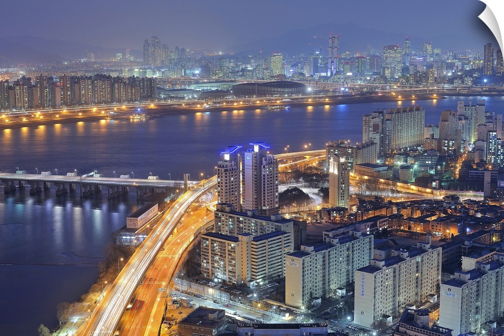 Big canvas photo of a city in Korea lit up at night along the water.