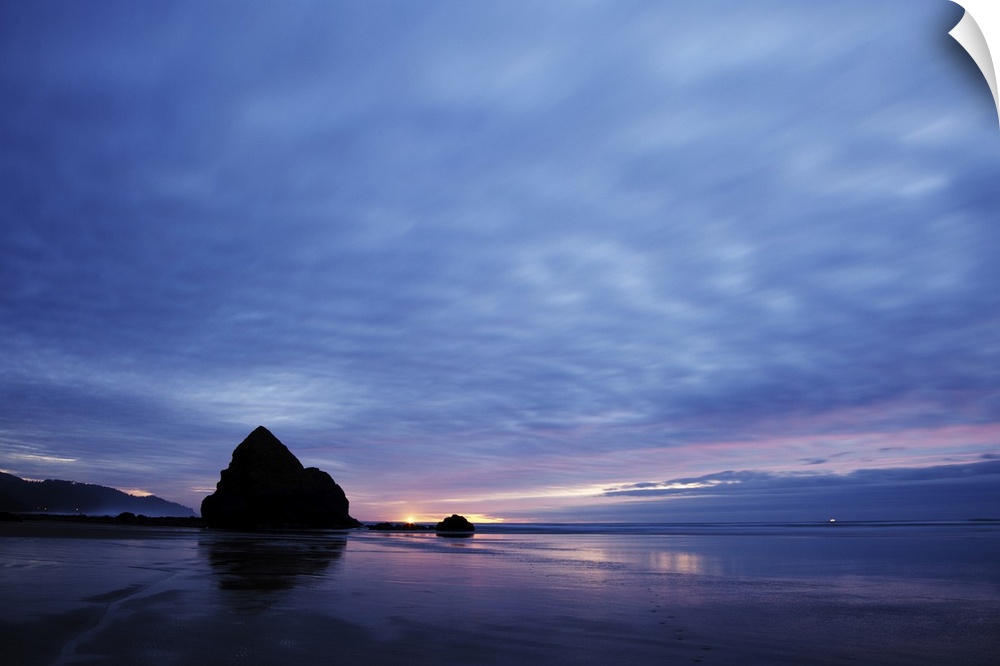 Pacific ocean, Cannon Beach, OR after the sunset. Small yellow light on the horizon is a lighthouse light.