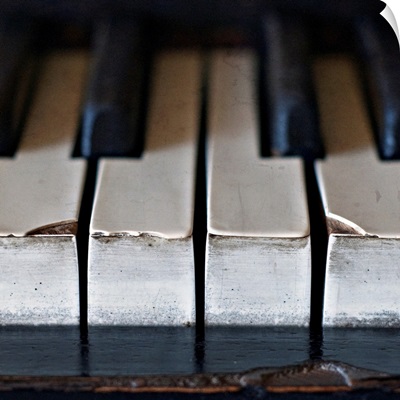 Old, antique upright piano keys displaying wear and tear.