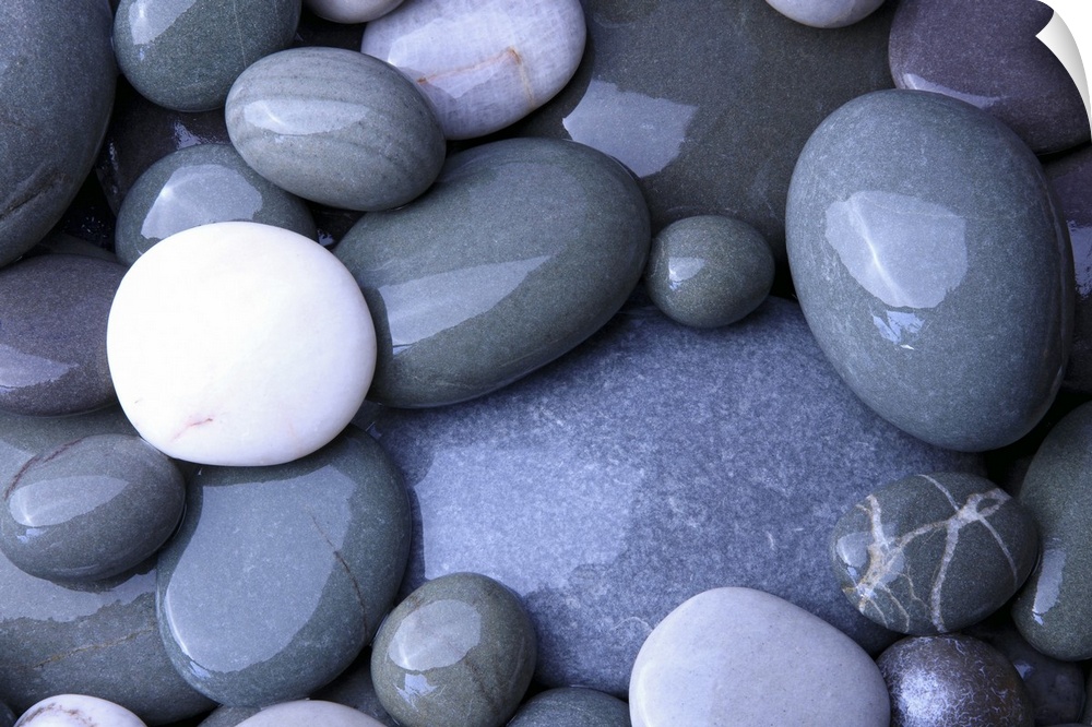 Close up photo of wet, smooth stones in varying oval shapes and gray colors.