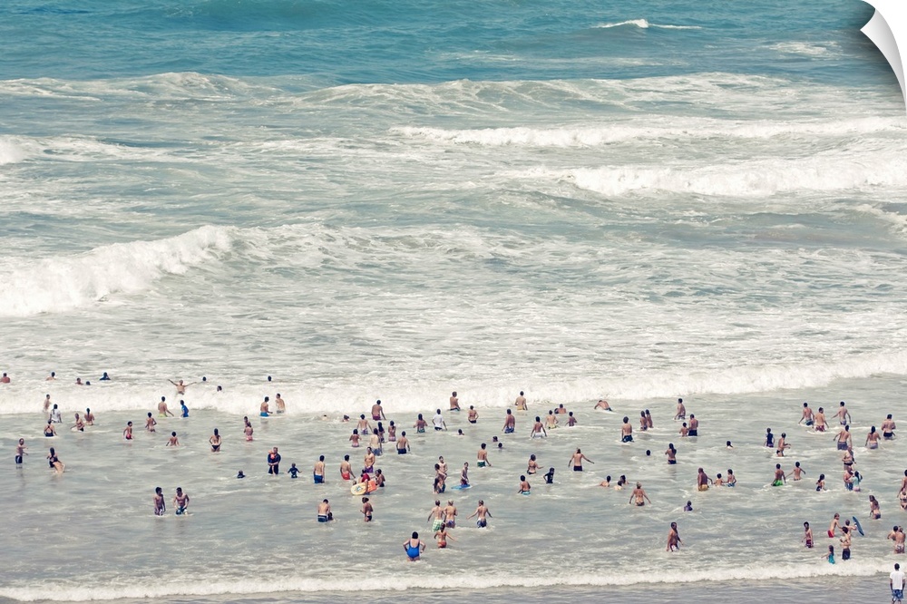 People walking into ocean wearing swimwear.