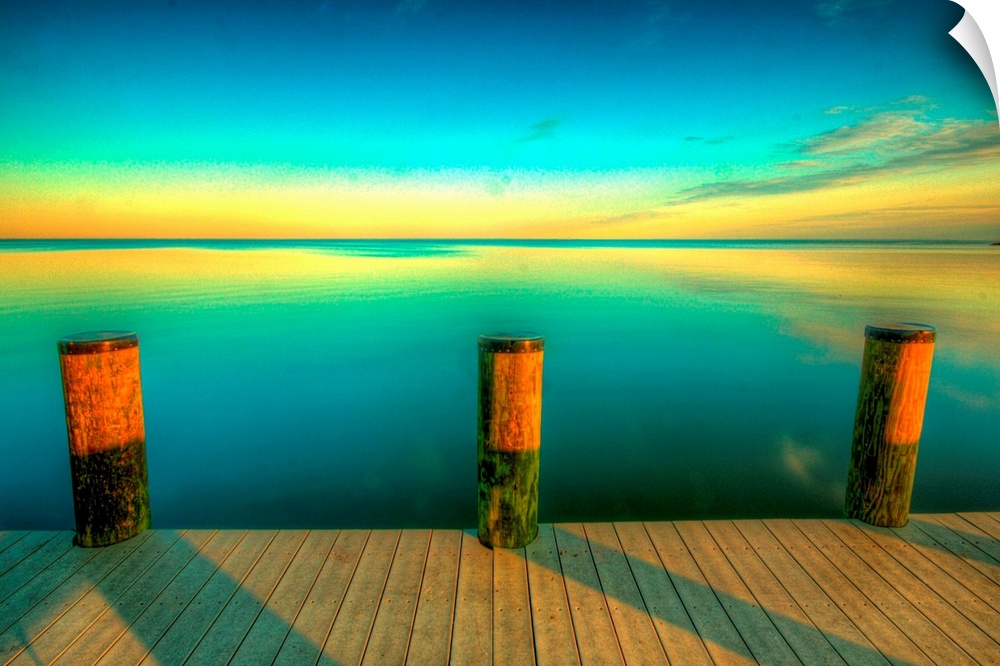 Big canvas photo art of a dock looking off onto calm water at sunset with the sky colors reflecting off of the water.