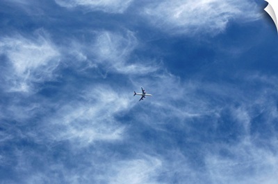 Plane in cloud filled blue sky.