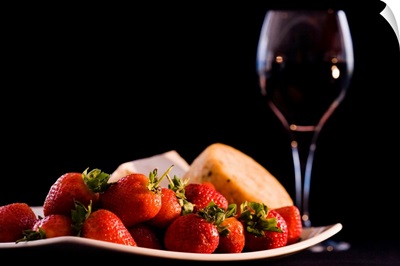 Plate of strawberries and cheeses by glass of red wine