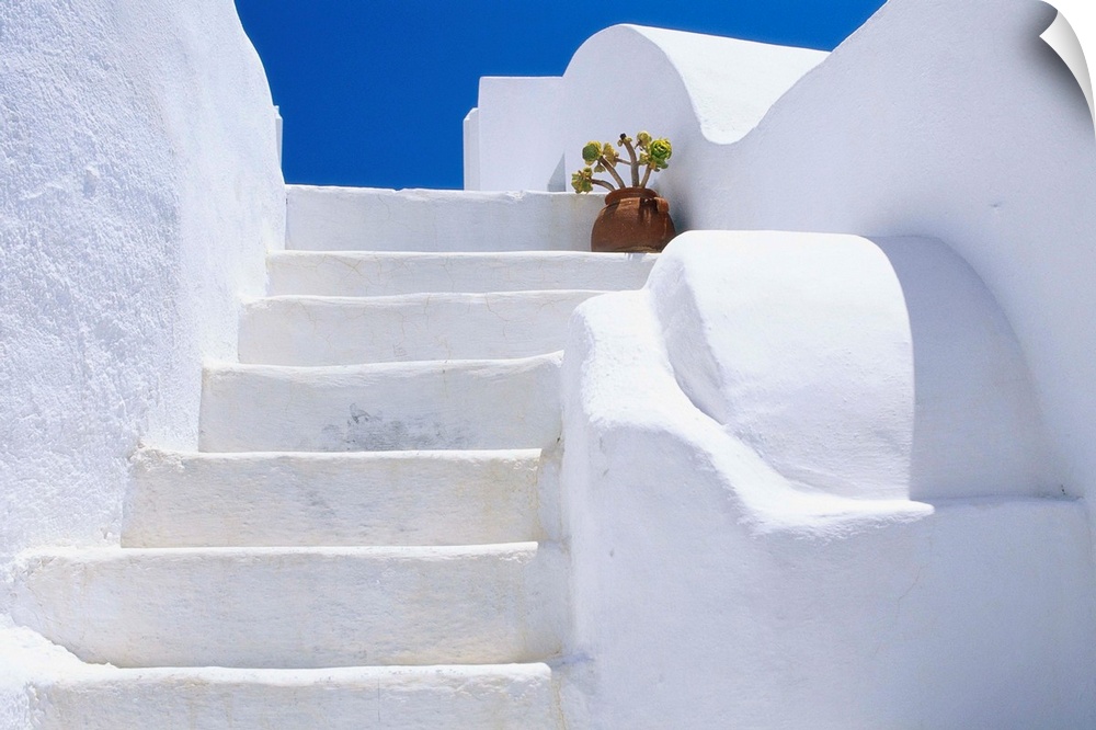 Potted flowers at the top of a white staircase on Santorini Island in Greece.