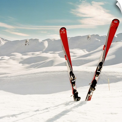 Red pair of ski standing in snow. Mountains in background