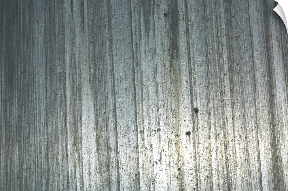 Big, horizontal photograph of a shiny metal surface with vertical streaks and a rough, pitted texture.