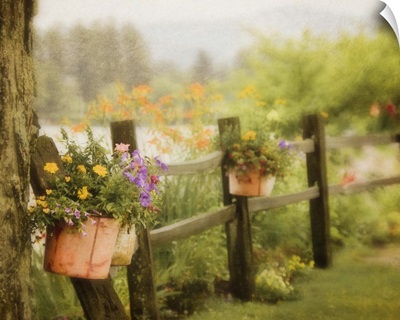 Rustic wooden fence with flowers in clay pots hanging on posts