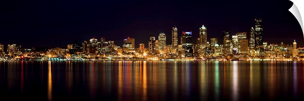 Nighttime shot of downtown Seattle at night with lights of city reflected in water of Puget Sound.