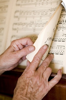 Senior's hands turning page of sheet music