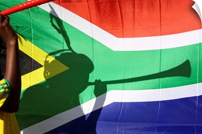 Shadow of soccer supporter blowing vuvuzela, South African flag in background