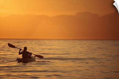 Silhouette of a Woman in a Sea Kayak at Sunset