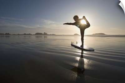 silhouette of female surfer doing bow pulling yoga pose