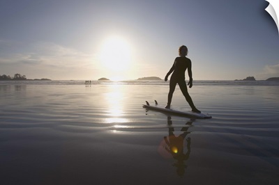 silhouette of female surfer doing yoga stretches