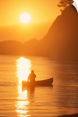 Silhouette of person canoeing at sunset