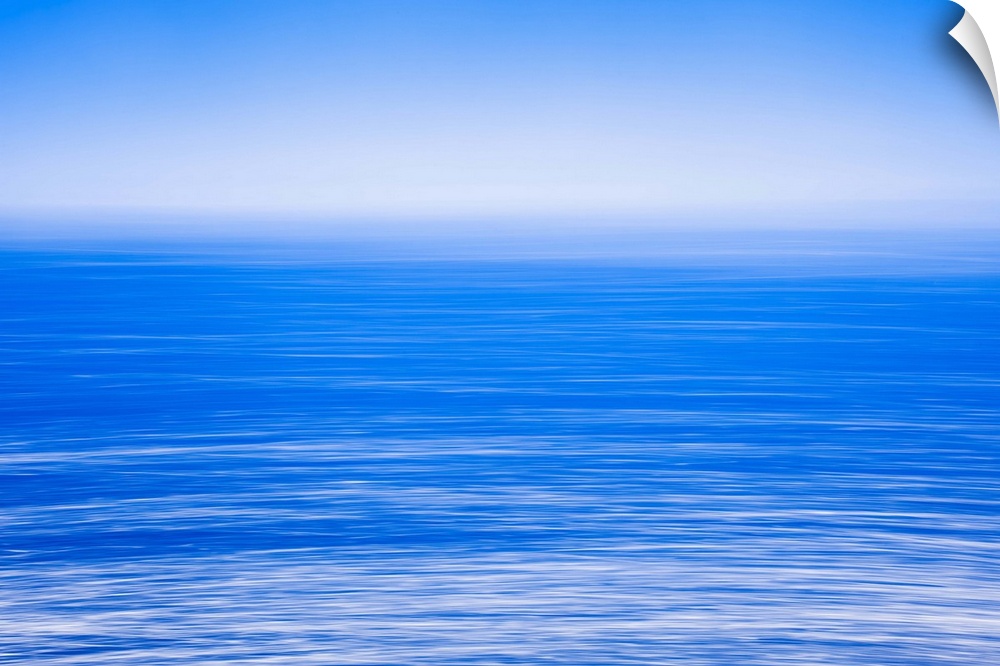 Silky calm blue open sea [ocean] with fog or mist over water. Blue sky.