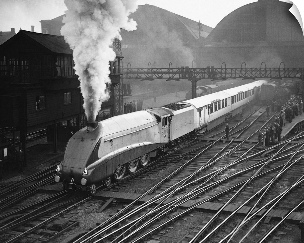 The gleaming Silver Link emits a jet of steam as it passes a platform crowded with onlookers.